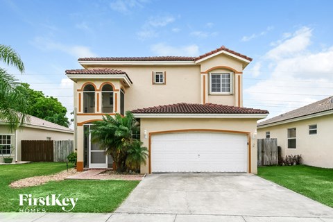 a beige house with a garage and a palm tree