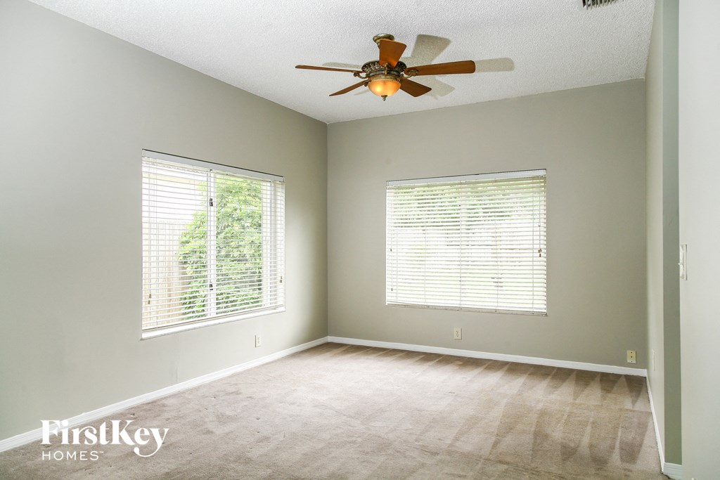 an empty room with a ceiling fan and two windows