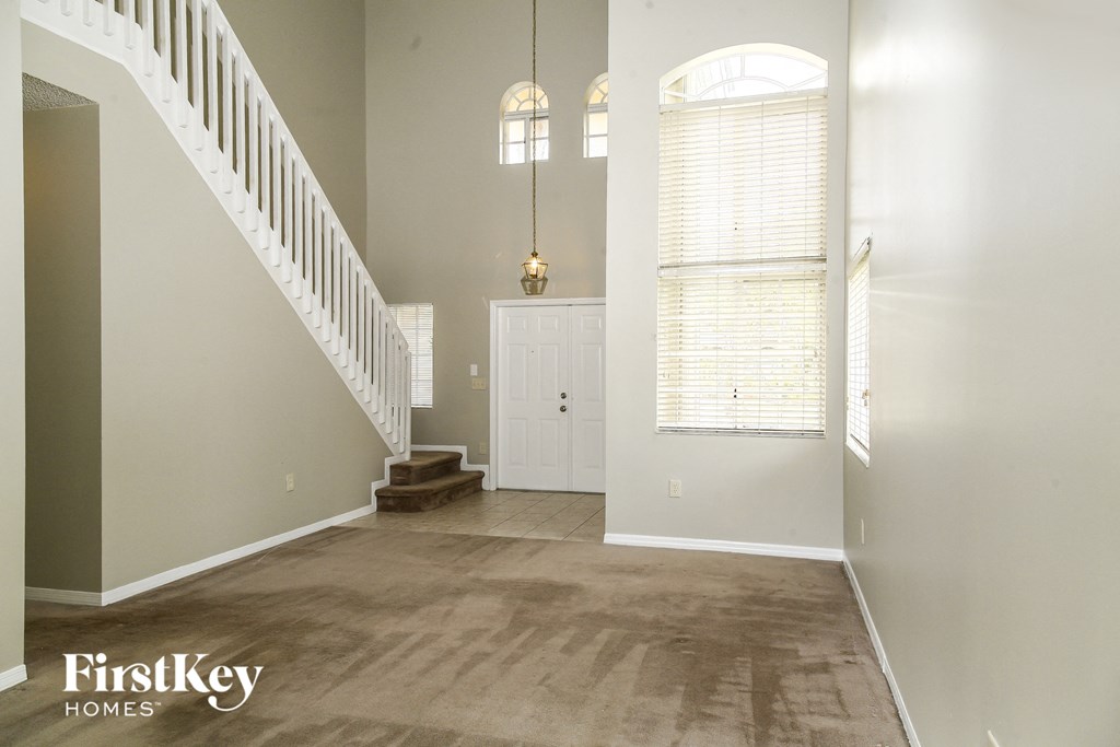 an empty living room with a staircase and a white door