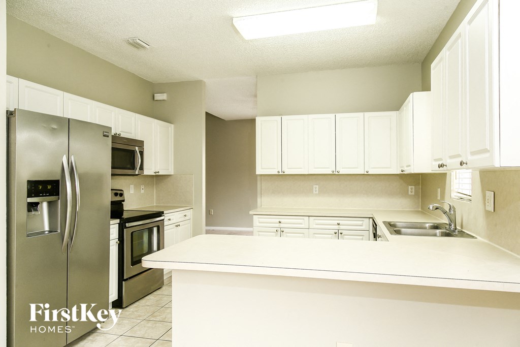 a white kitchen with stainless steel appliances and white counter tops