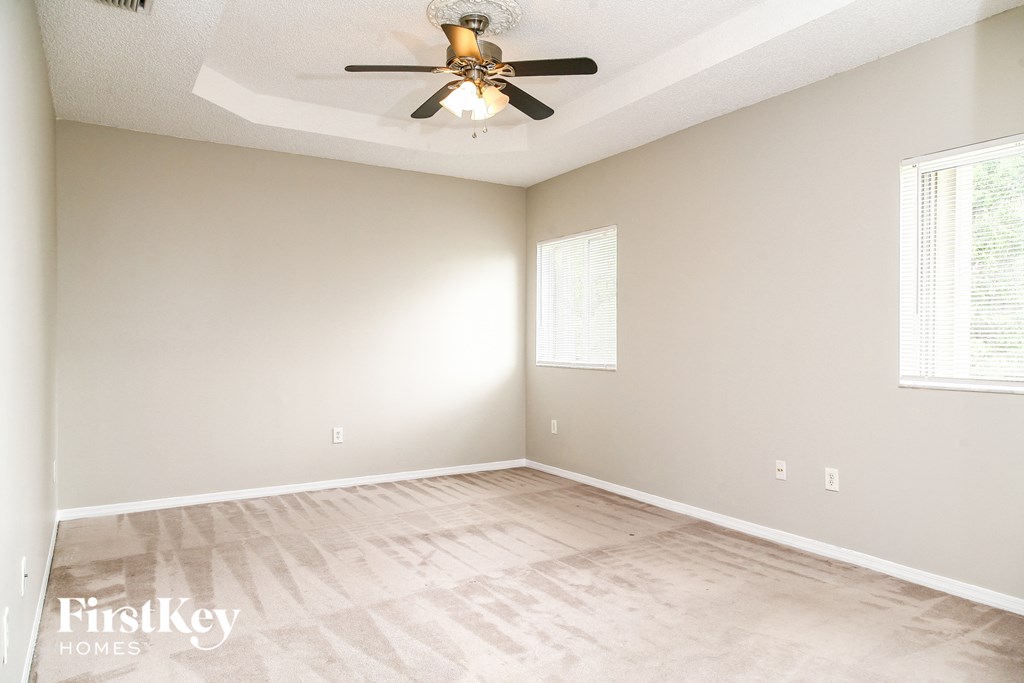 a empty living room with a ceiling fan and wood floors