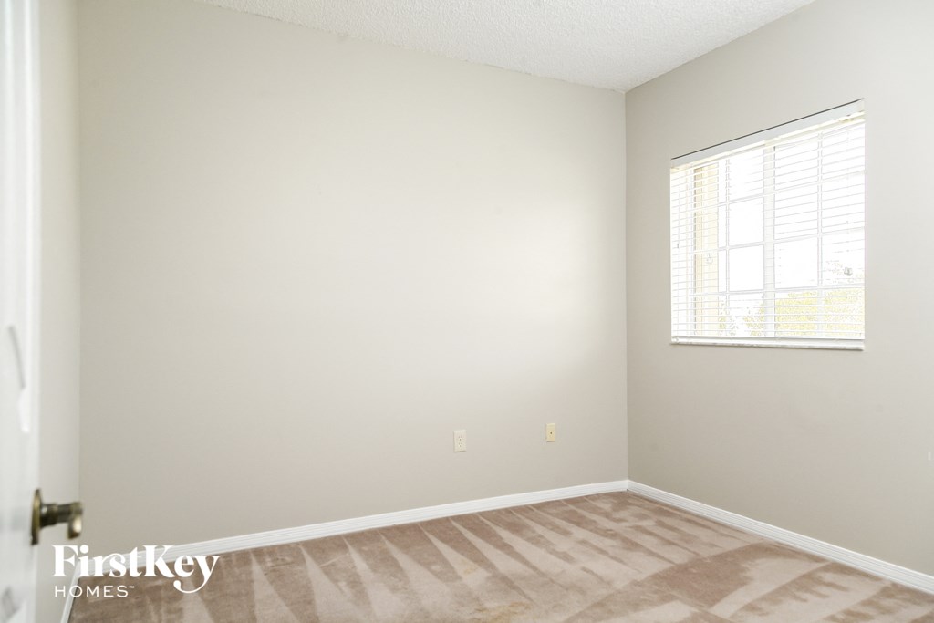 a bedroom with white walls and a window and wooden floors