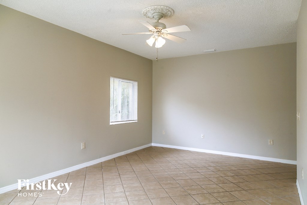 an empty living room with a ceiling fan and tiled floor