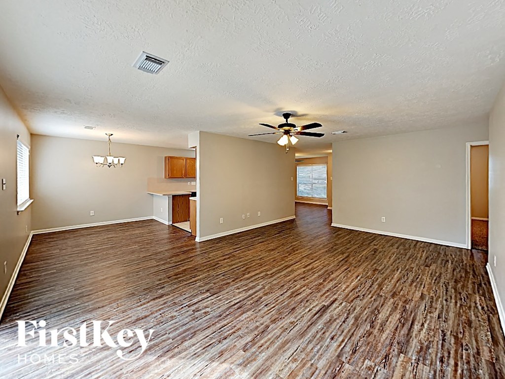 an empty living room with a wood floor and a ceiling fan