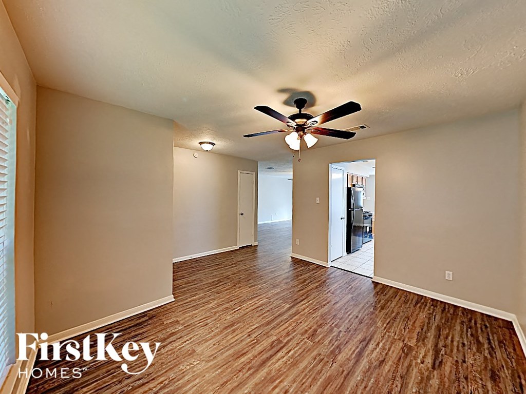 a spacious living room with wood flooring and a ceiling fan