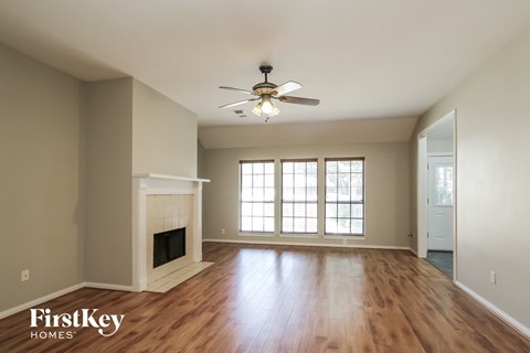 A spacious room with a fireplace and a ceiling fan.