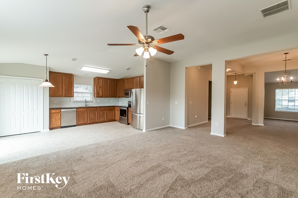 an empty living room and kitchen with a ceiling fan