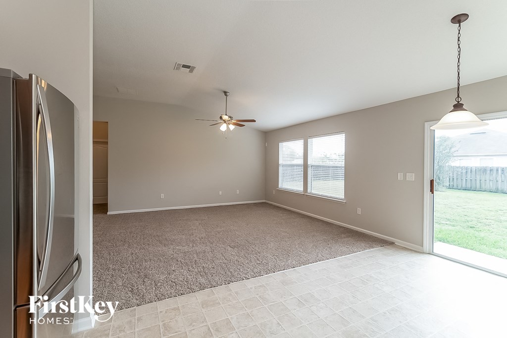 an empty living room with a large window and a ceiling fan