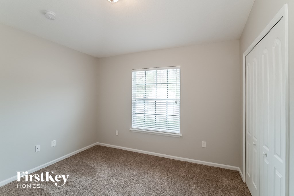 a bedroom with carpet and a window and a closet