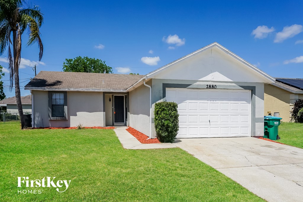 A house with a garage and a palm tree in front.