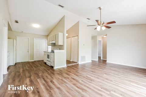 A spacious kitchen and living room with wooden floors and white walls.