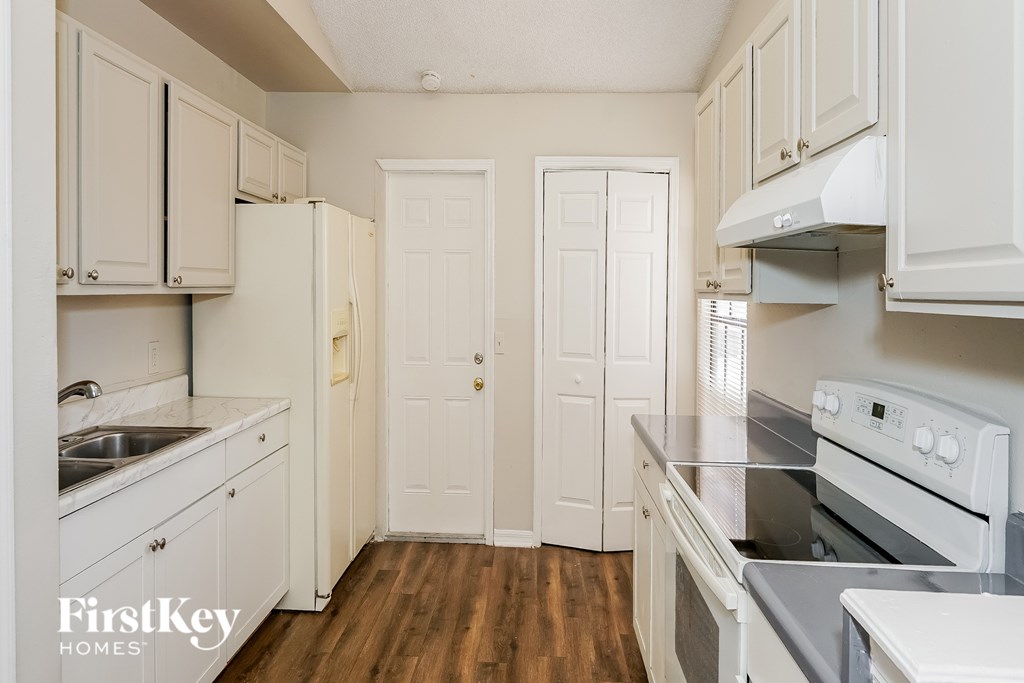 A kitchen with white cabinets and appliances.