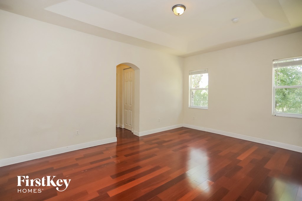 an empty living room with wood floors and white walls
