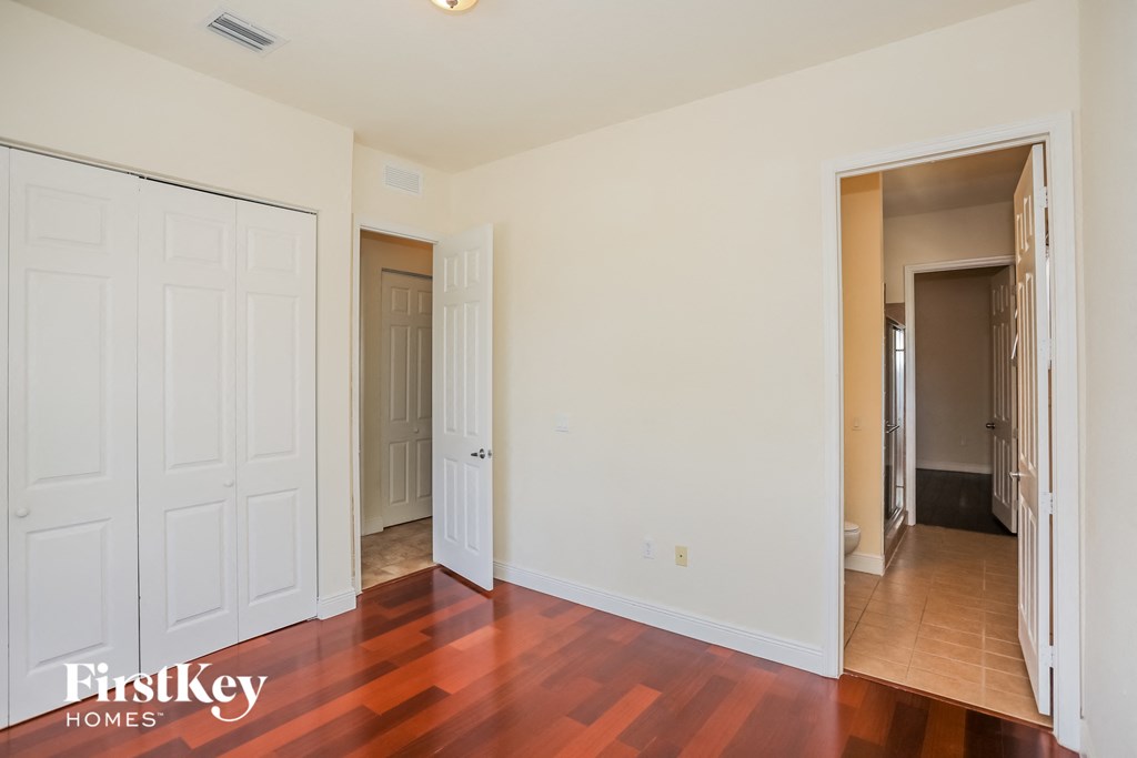 a bedroom with two closets and a door to a hallway and a wood floor