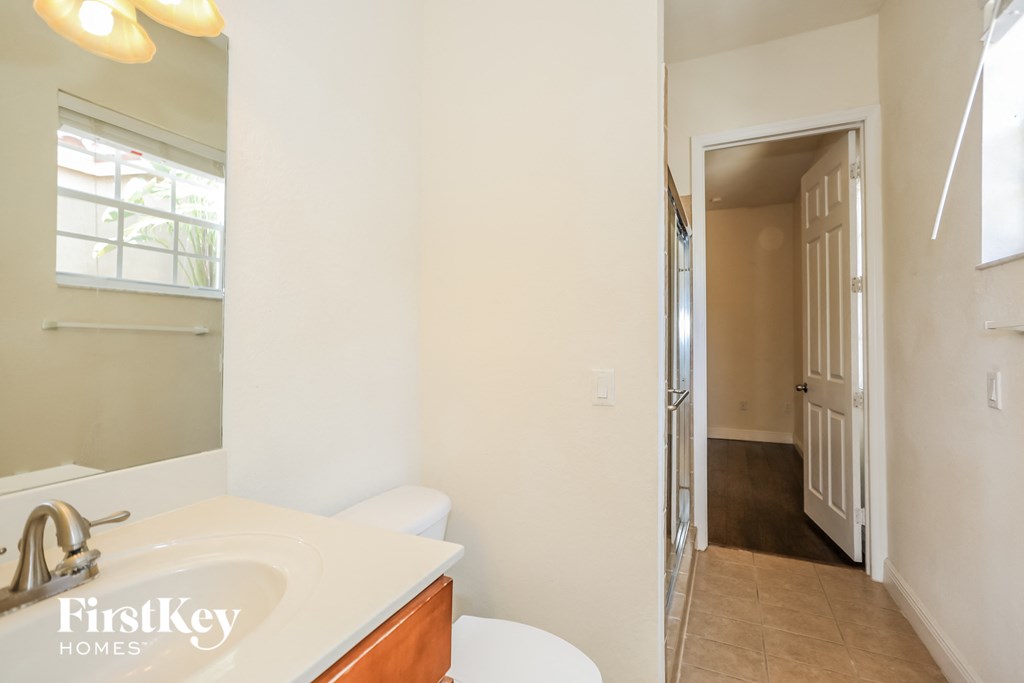 a bathroom with a sink and a mirror and a hallway with a door
