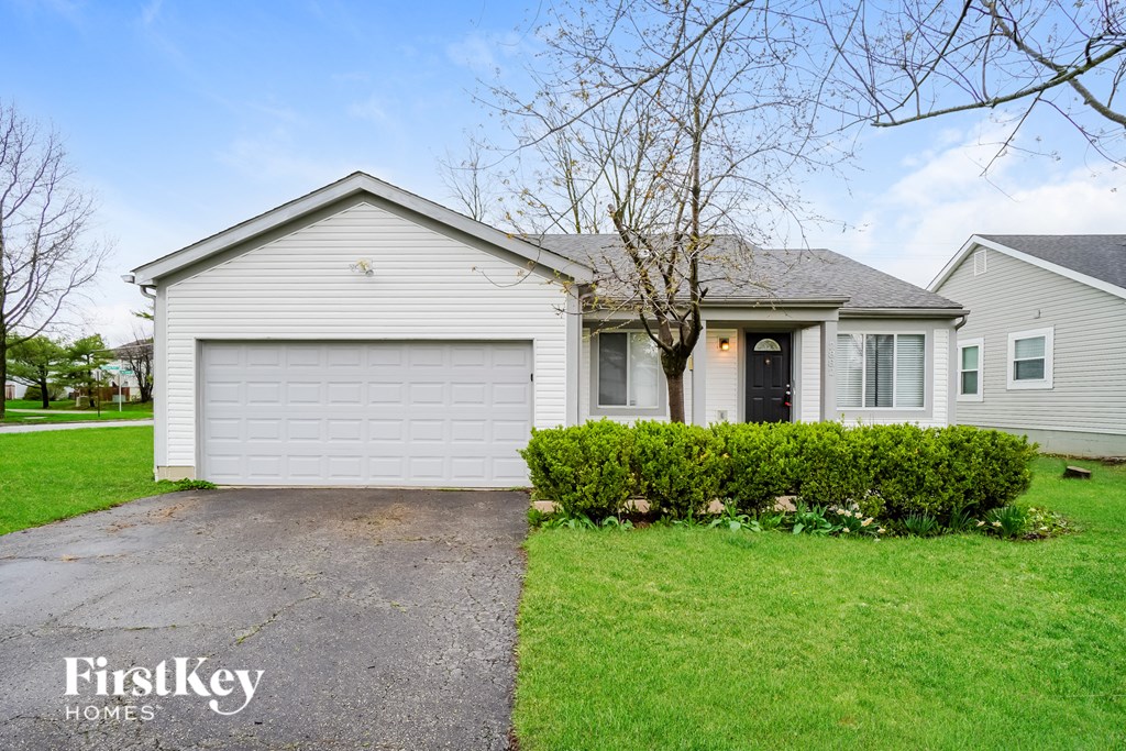 A house with a garage and a tree in front of it.