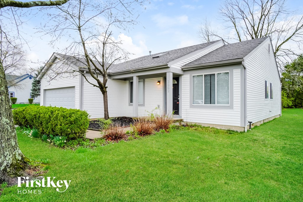 A white house with a tree in front of it.