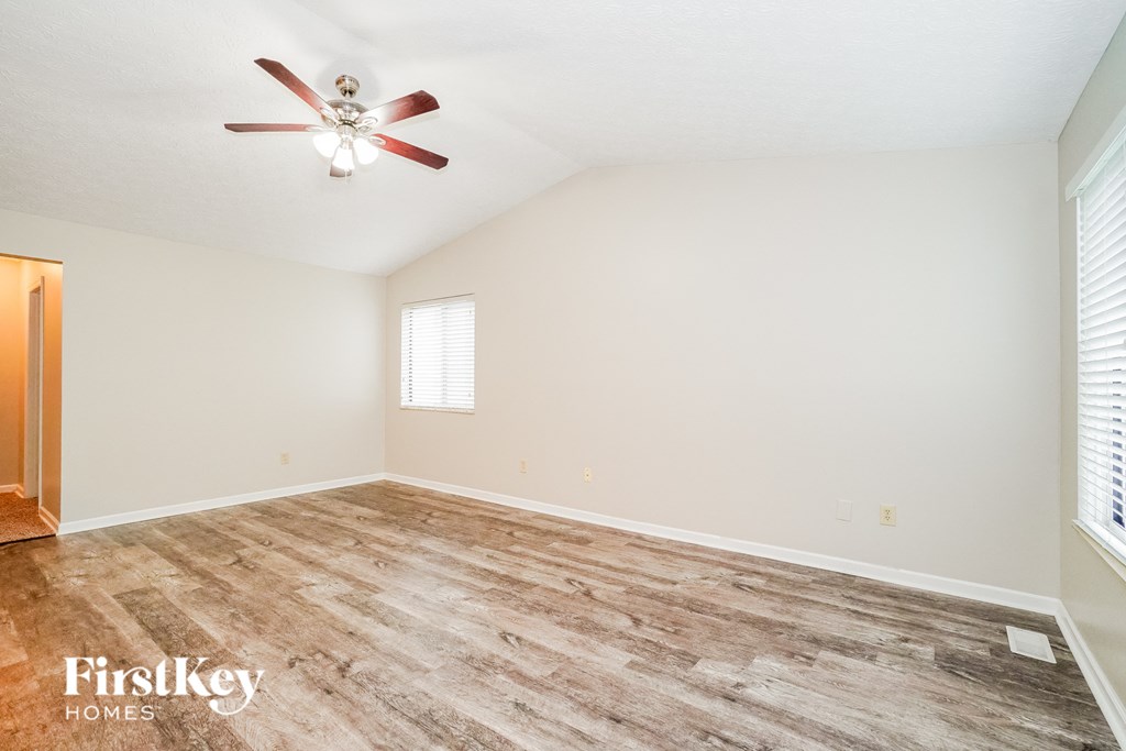 A room with a ceiling fan and wooden flooring.