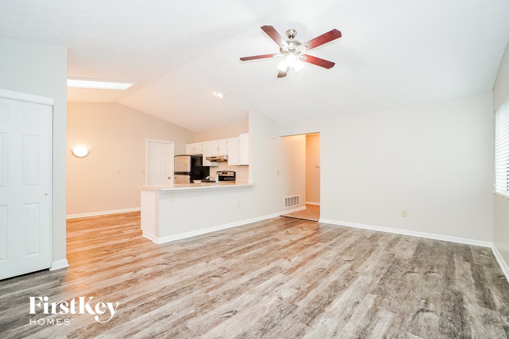 A spacious room with a ceiling fan and wooden flooring.