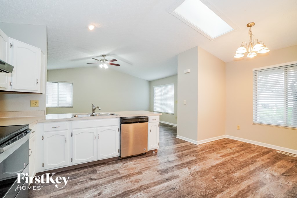 A kitchen with white cabinets and a wooden floor.