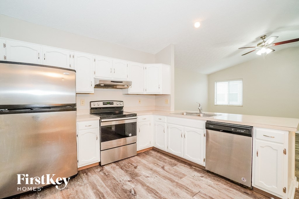 A kitchen with white cabinets and a stainless steel refrigerator.
