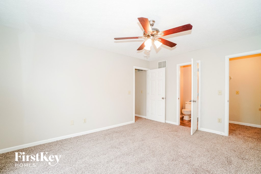 A room with a ceiling fan and a carpeted floor.