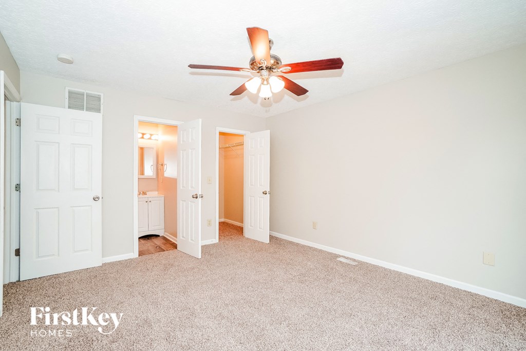 A spacious room with a ceiling fan and a carpeted floor.