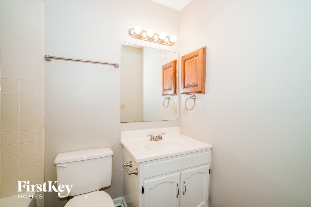 A white bathroom with a toilet, sink, and mirror.