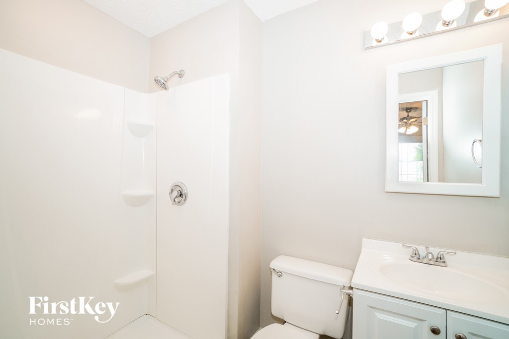 A white bathroom with a toilet, sink, and shower.