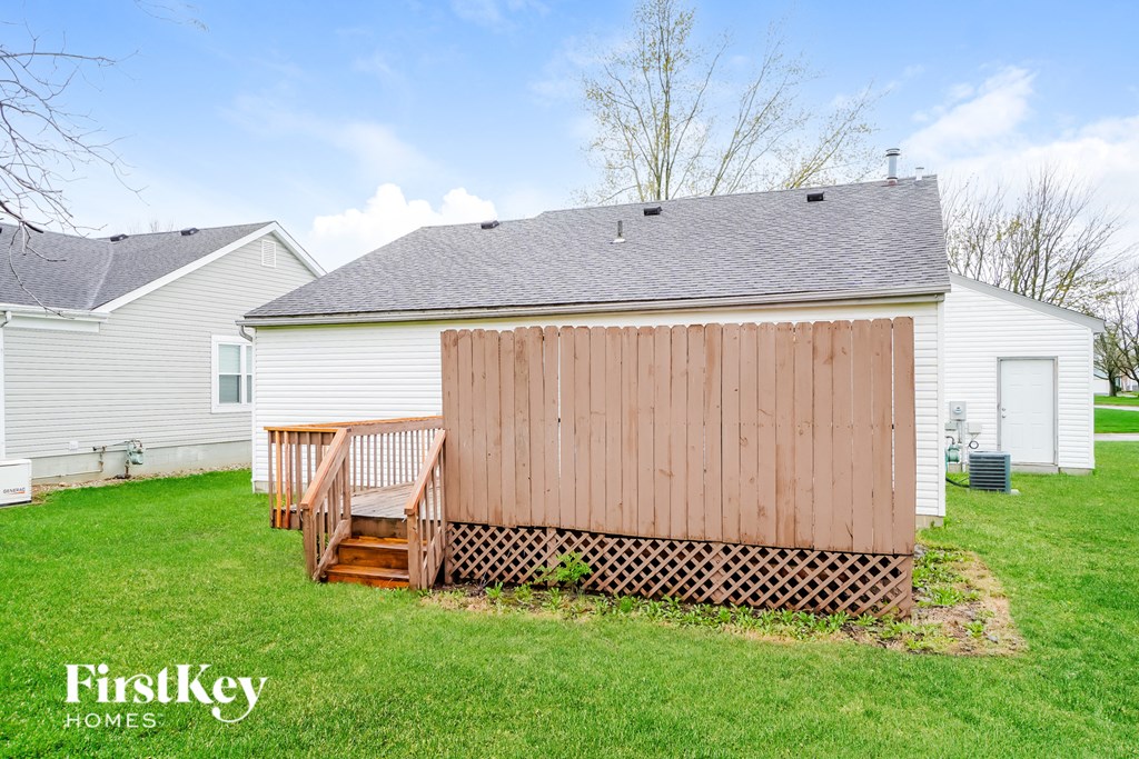 A wooden shed with a brown door and a lattice fence.
