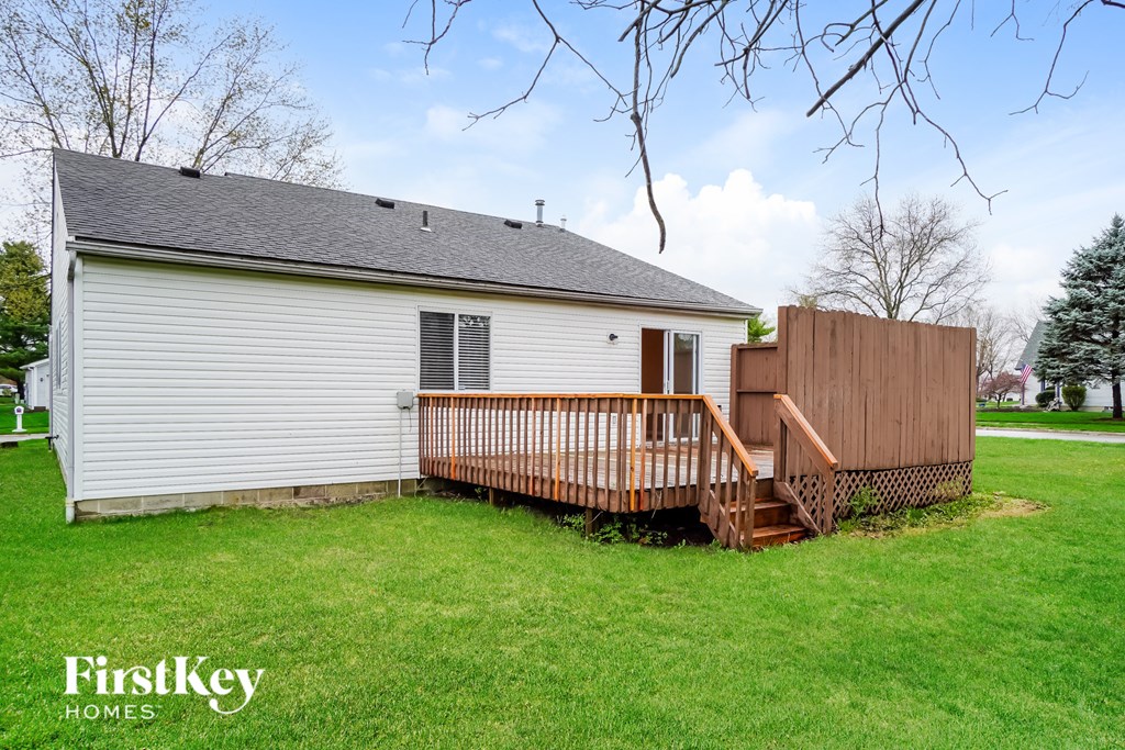 A house with a deck and a tree in the background.