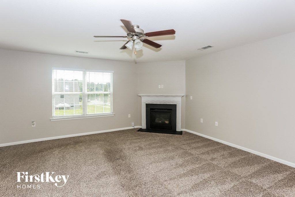 A spacious room with a fireplace and a ceiling fan.
