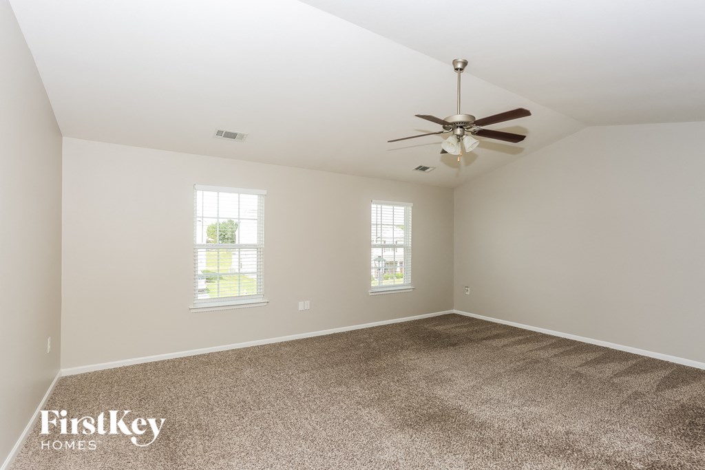 A room with a carpet floor and a ceiling fan.