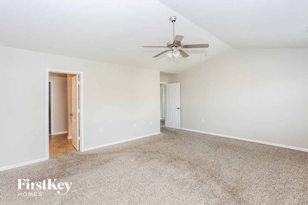 A spacious room with a carpeted floor and a ceiling fan.
