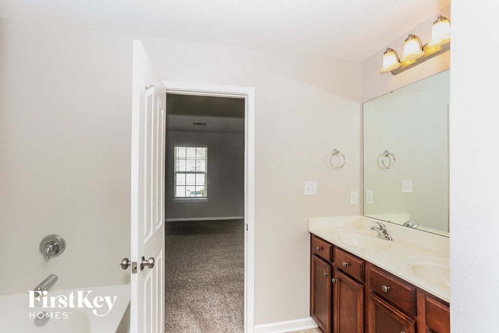 A bathroom with a sink, mirror, and a door leading to another room.