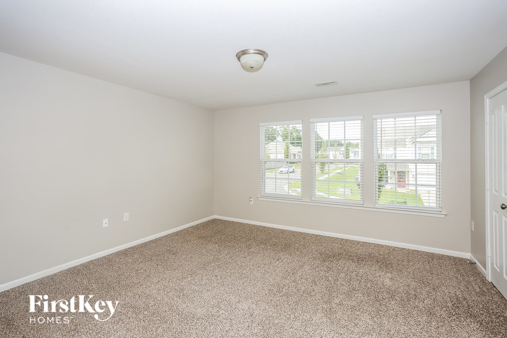 A room with a carpeted floor and a window with blinds.