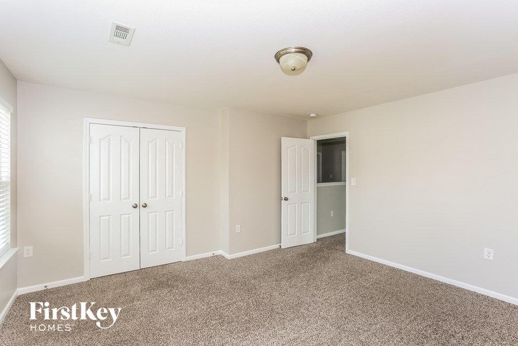 A carpeted room with two doors and a window.