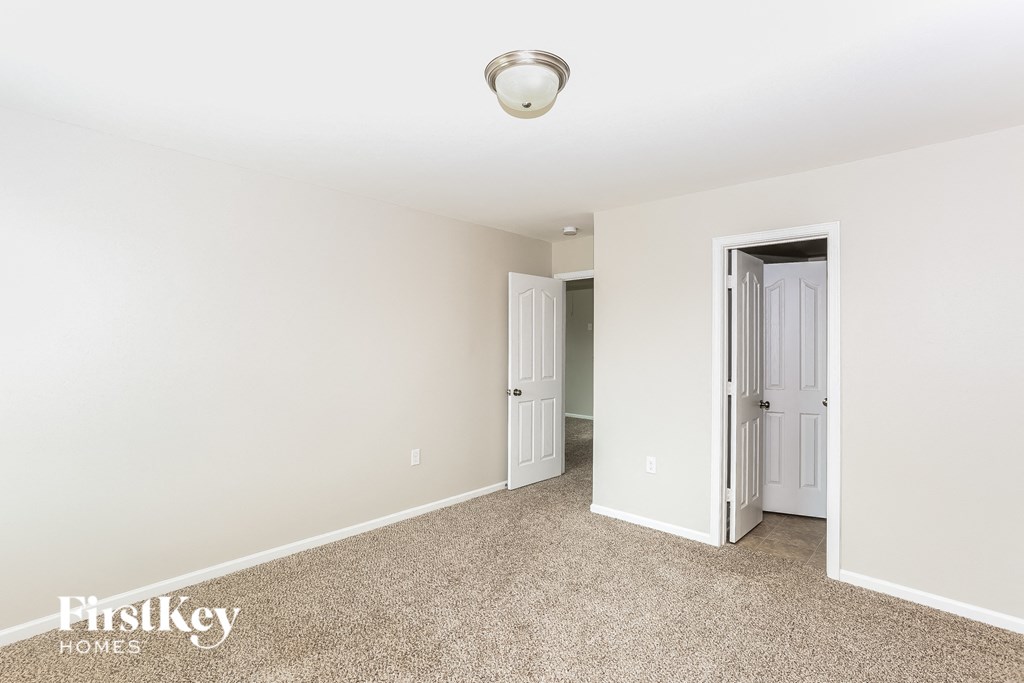 A carpeted room with a door open to another room.