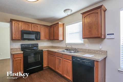 A kitchen with wooden cabinets and black appliances.