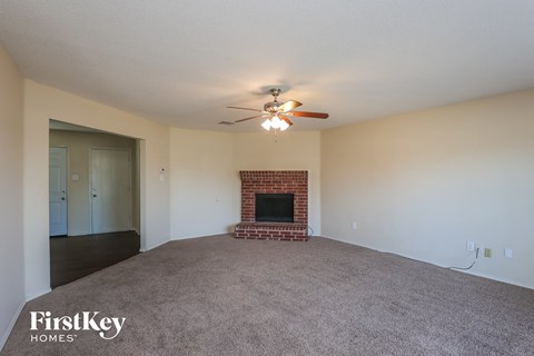 A spacious living room with a fireplace and a ceiling fan.