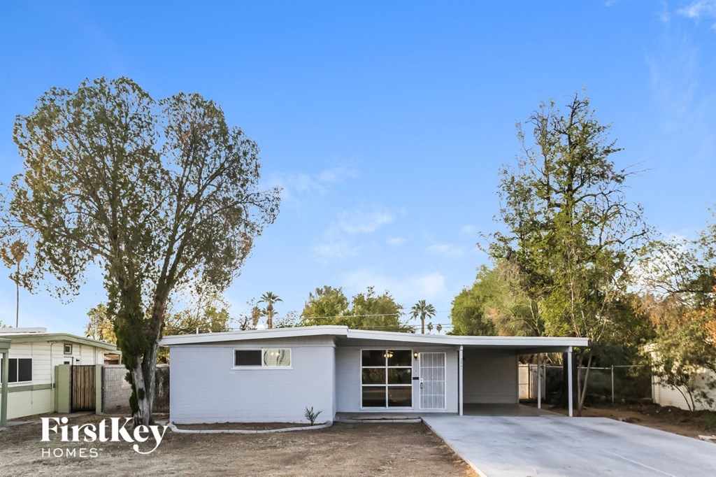 the exterior of a white house with trees and a driveway
