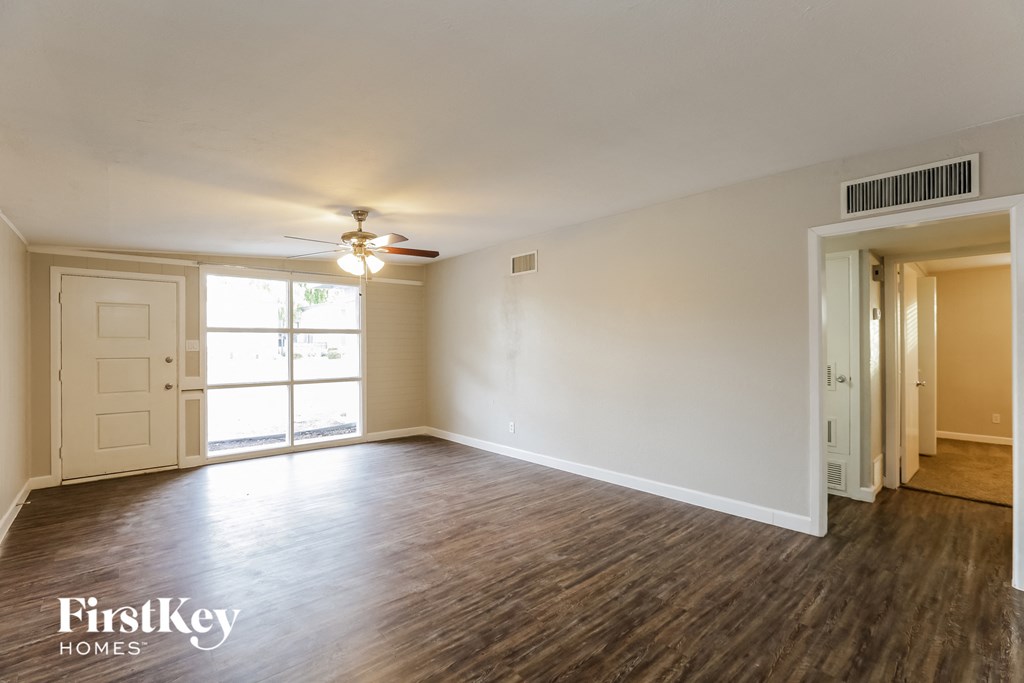 an empty living room with wood flooring and a ceiling fan