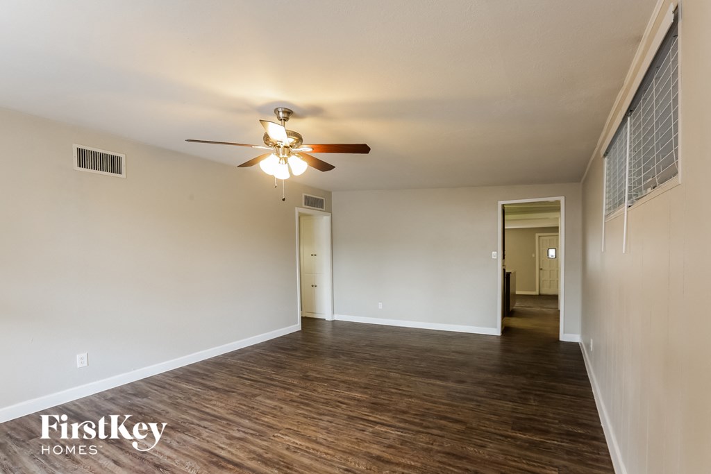 an empty living room with wood flooring and a ceiling fan