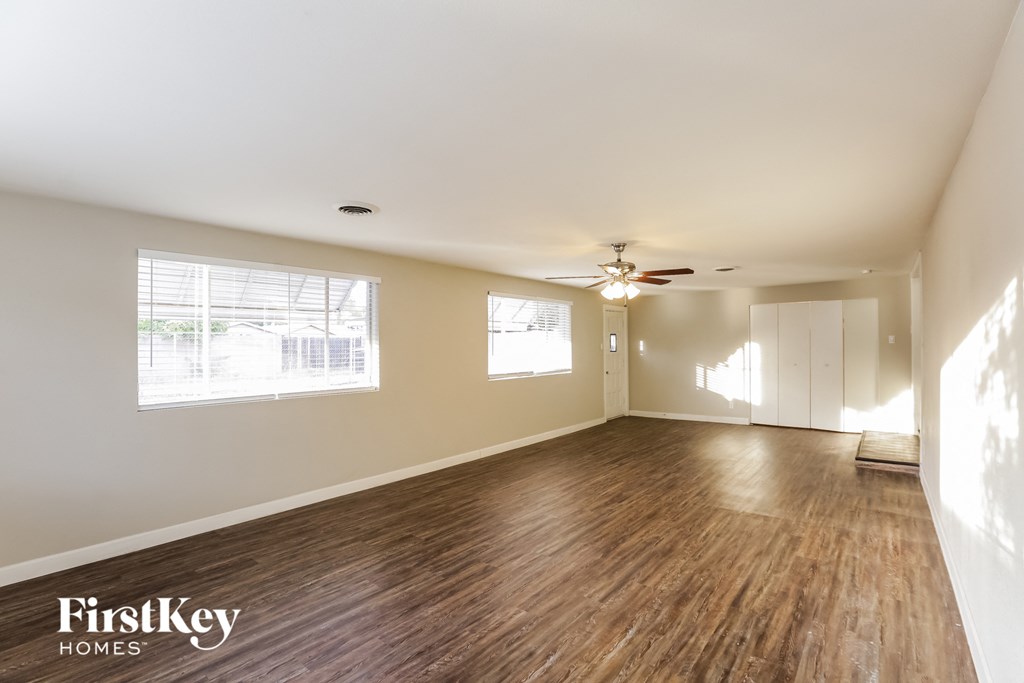an empty living room with wood floors and a ceiling fan