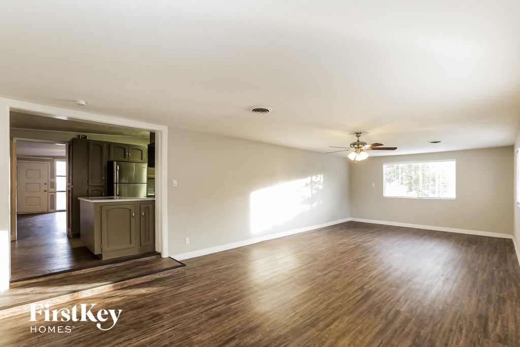 an empty living room with wood floors and a ceiling fan