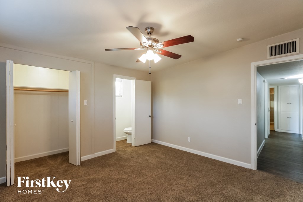 an empty living room with a ceiling fan and a closet
