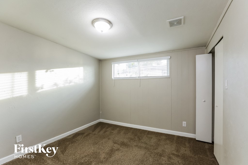the living room of an apartment with carpet and a window