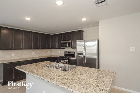 a kitchen with granite countertops and a stainless steel refrigerator