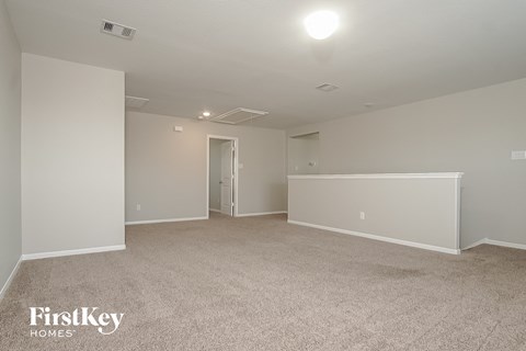 a spacious living room with carpet and white walls