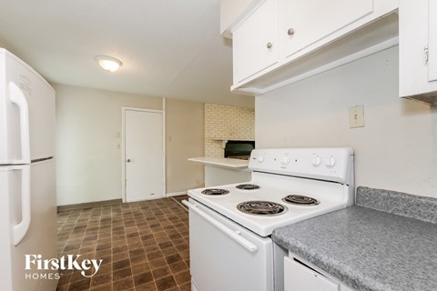 A kitchen with a white stove top oven and a white refrigerator.